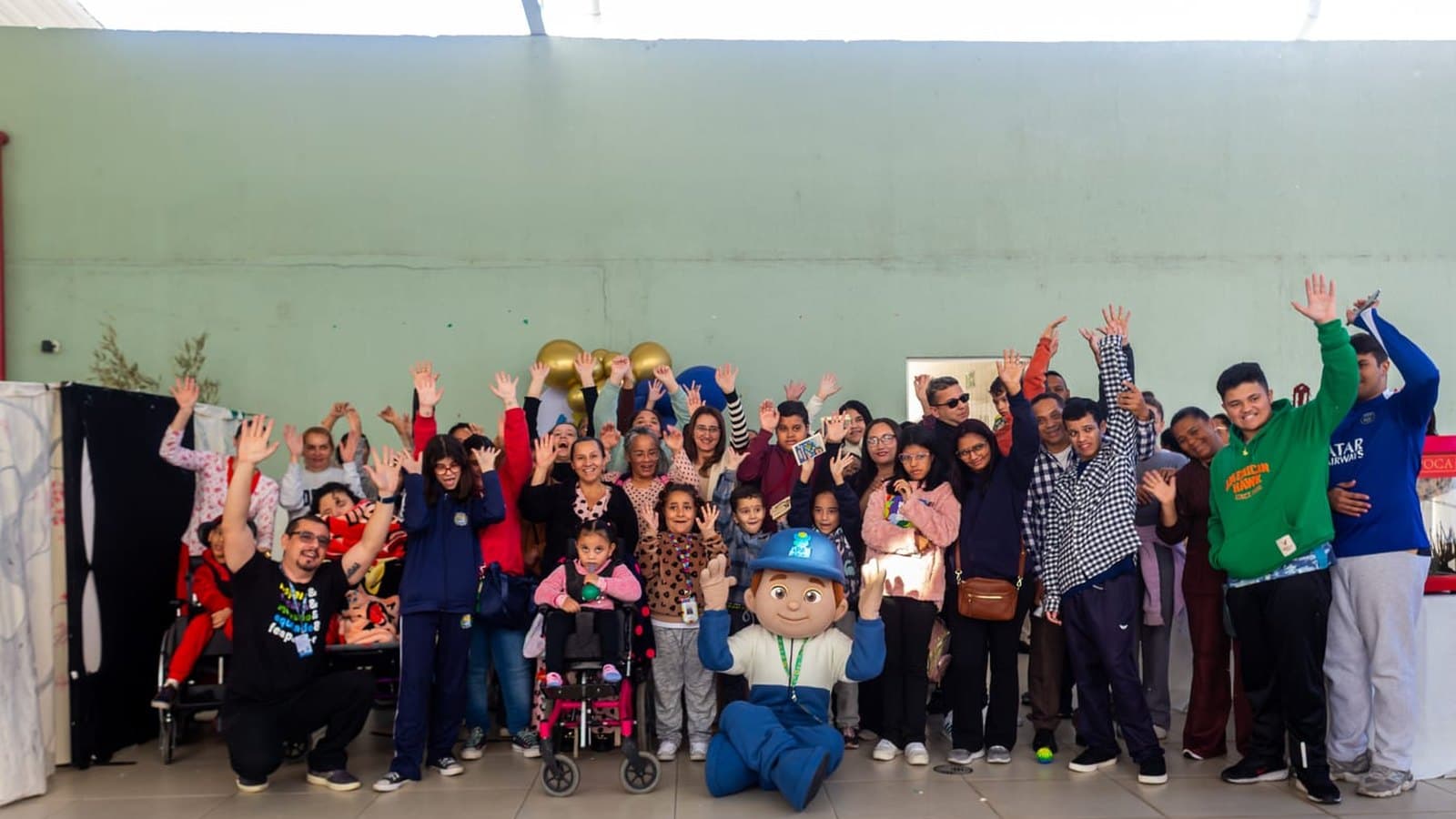 Atendidos, famílias e equipe da APAE Barueri reunidos com o APAEzito em uma celebração.