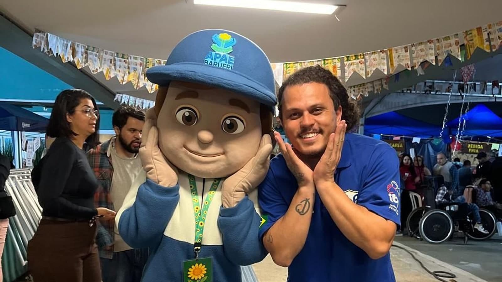 Apaezito, mascote da APAE Barueri, posa ao lado de participante durante evento comunitário