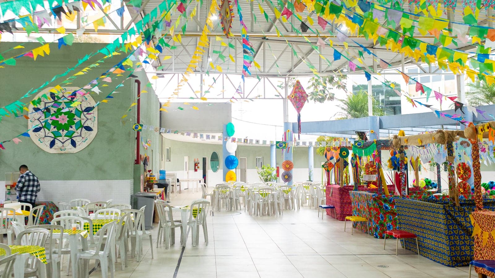 Salão da APAE Barueri decorado com bandeirinhas, girassóis e barracas para a Festa Junina