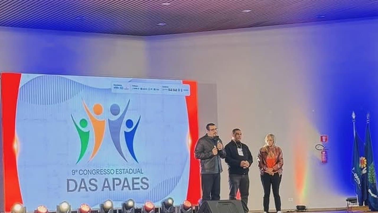 Palco do Congresso Estadual das APAEs, com a equipe apresentando.